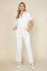 Model Wearing Skies Are Blue White Denim Utility Jumpsuit On A Yellow Background