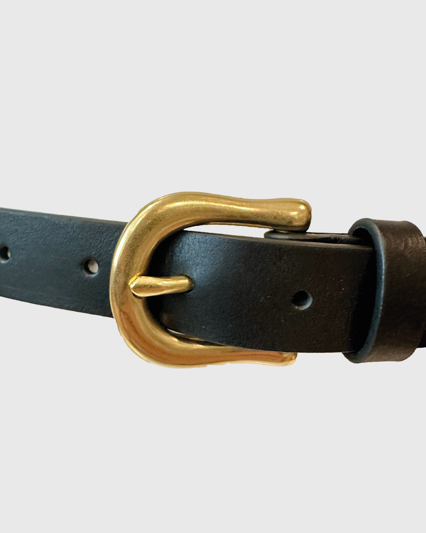 Black leather belt with a gold buckle on a light gray background