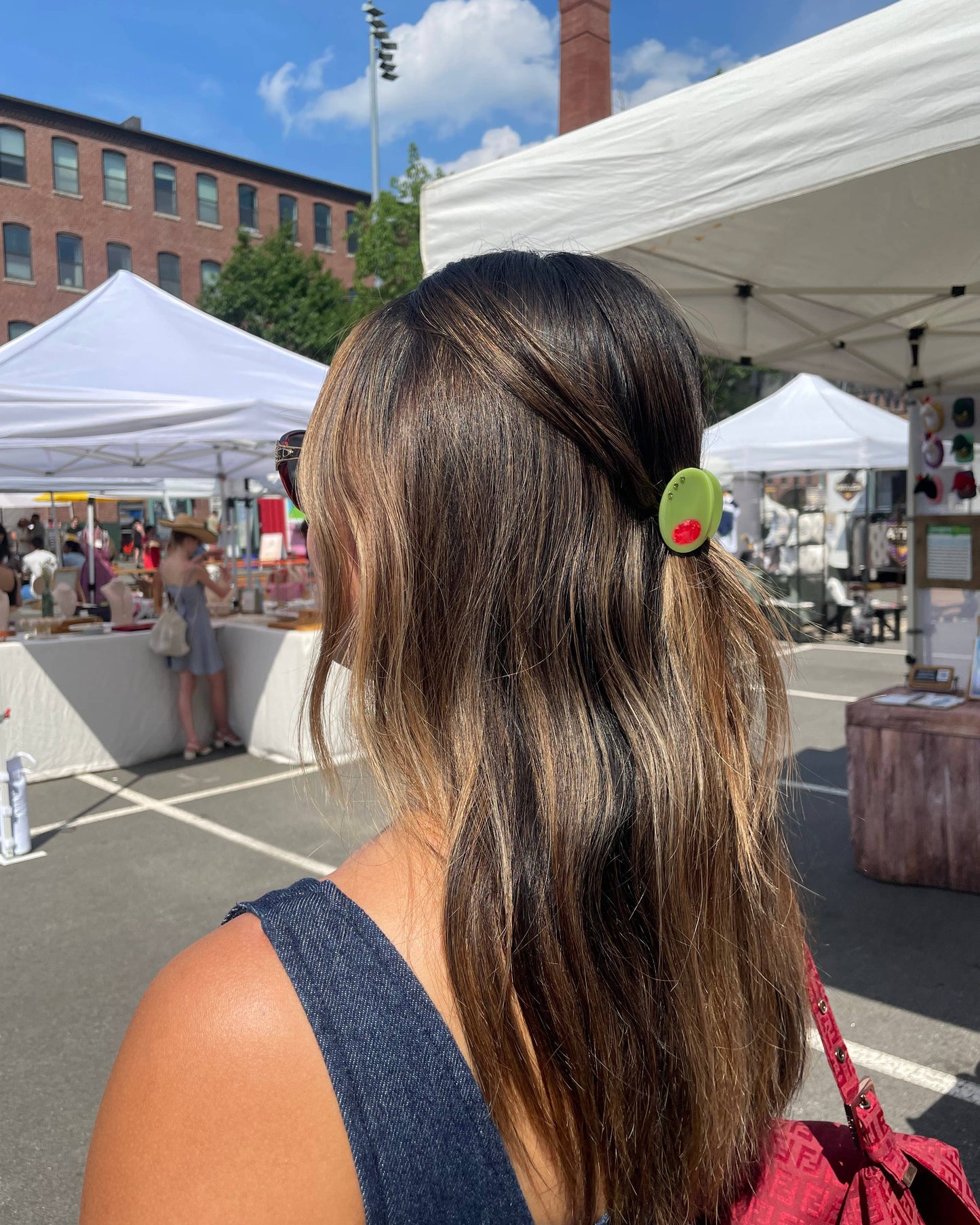 Woman wearing a green olive-shaped hair clip at an outdoor market