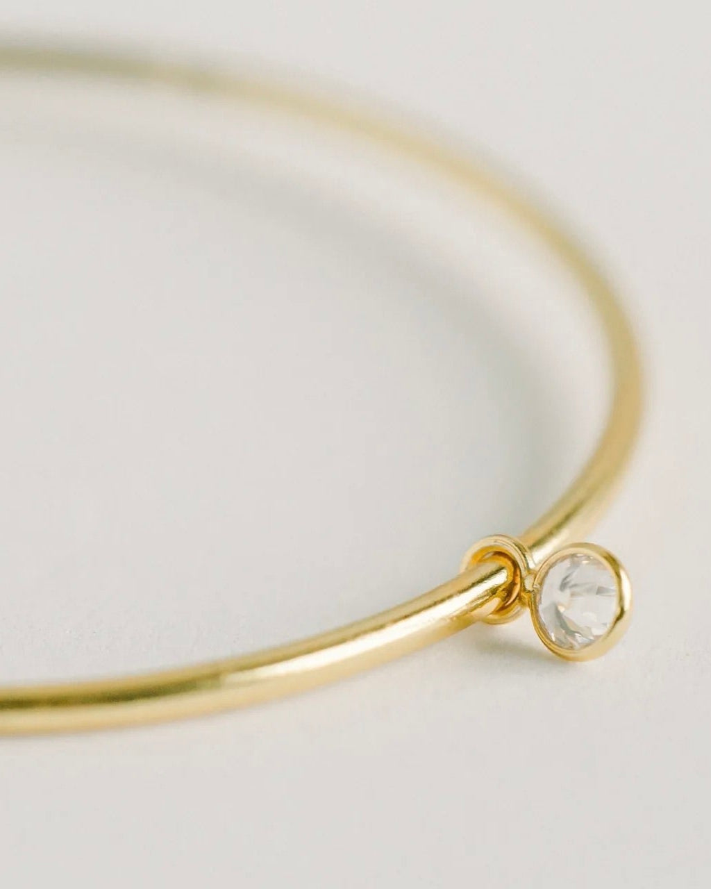 Close up photo of one earring of the Elli Parr Becca Gold Hoops, laying flat against a white background