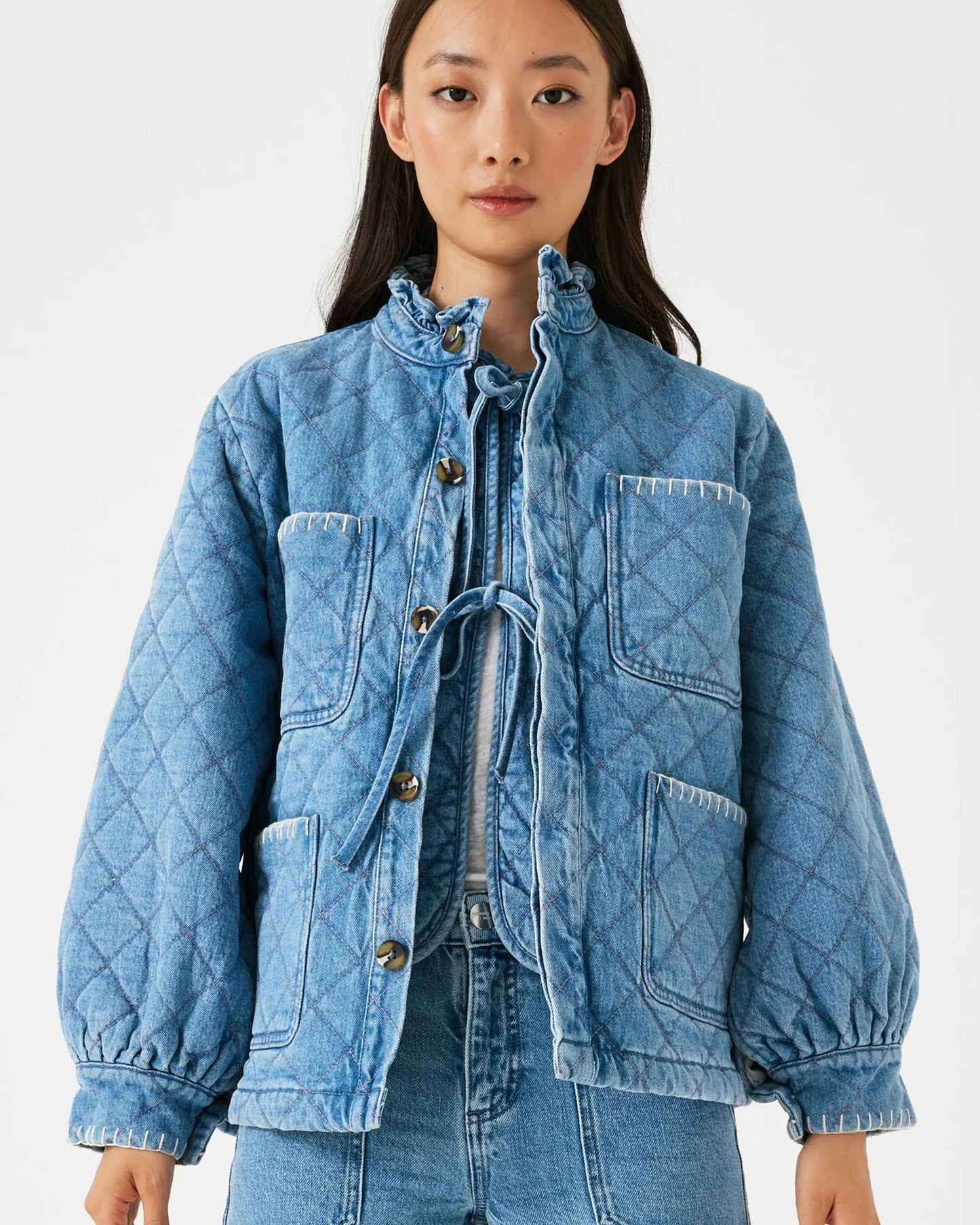 Model is wearing seventy + mochi Quilted Pablo Jacket in color rodeo vintage with light wash jeans on a white background