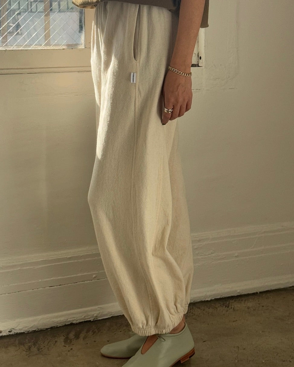 Side view of a model wearing the Le Bon Shoppe balloon pants in naturel sanding in front of a white wall