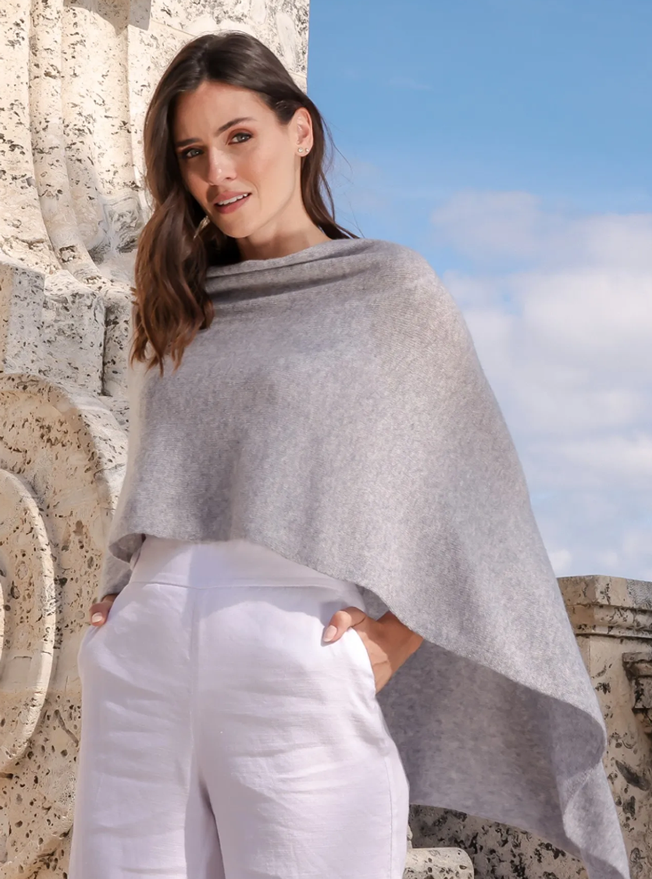 Woman wearing the Alashan Cashmere 100% Cashmere Dress Topper in Harbor against a stone structured