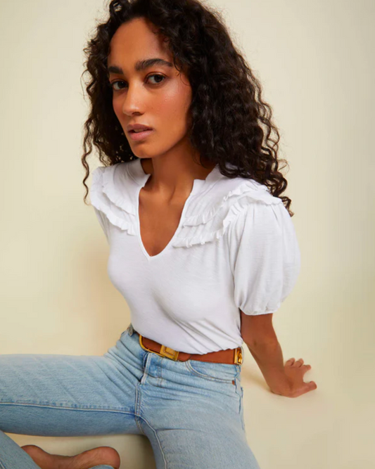 Model Wearing Nation LTD Judith Yoked Tee in White wearing jeans and brown belt on a beige background