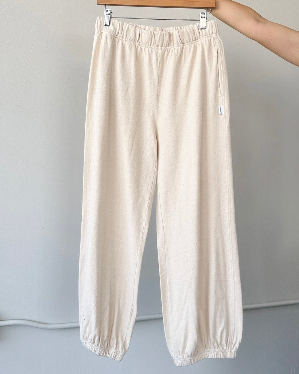 Front view of the Le Bon Shoppe balloon pants in naturel on a hanger being held up in front of a white wall