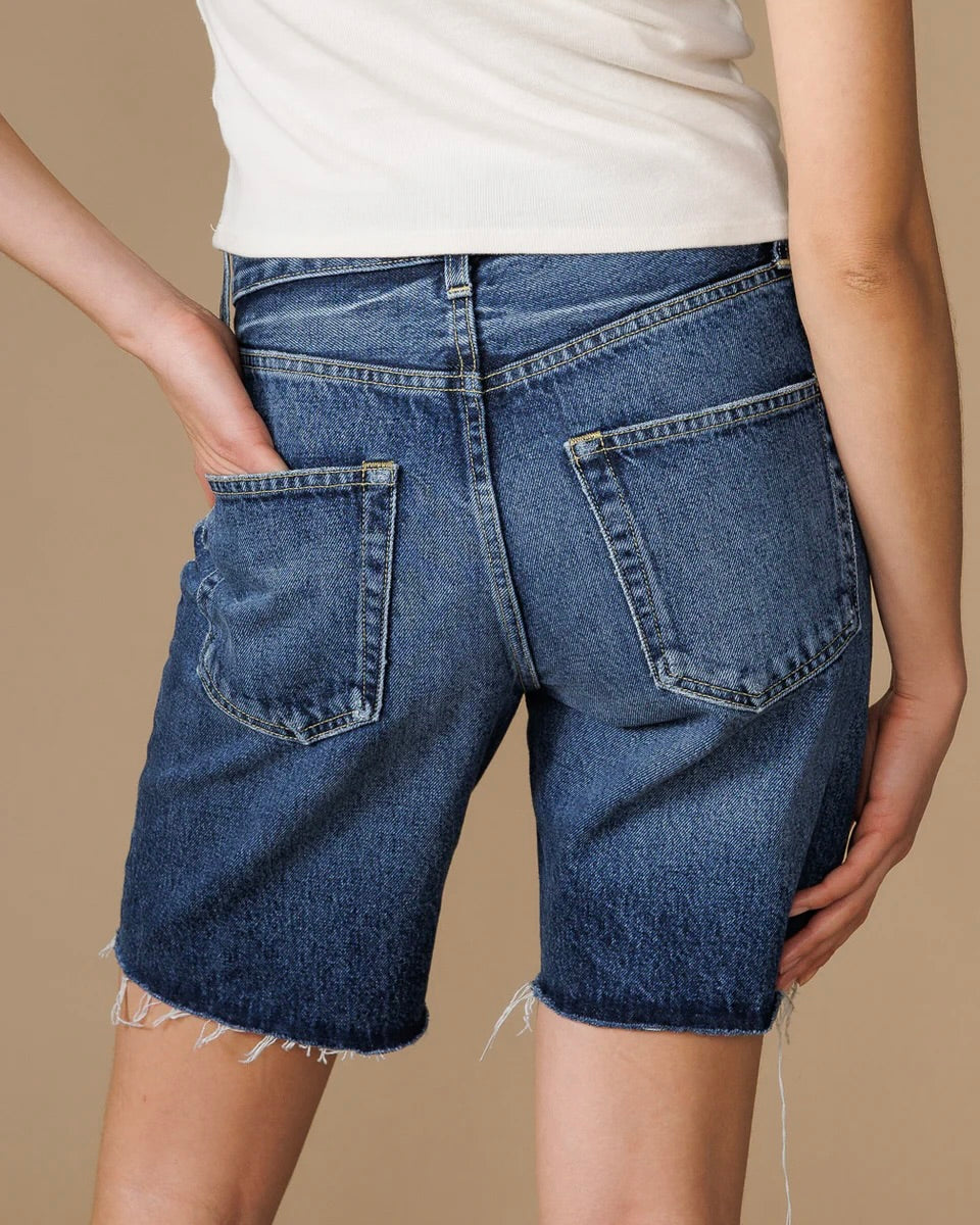 Close up back view of a model wearing the Edwin Sawyer Bermuda shorts in peck with hand in the back pocket standing in front of a neutral backdrop