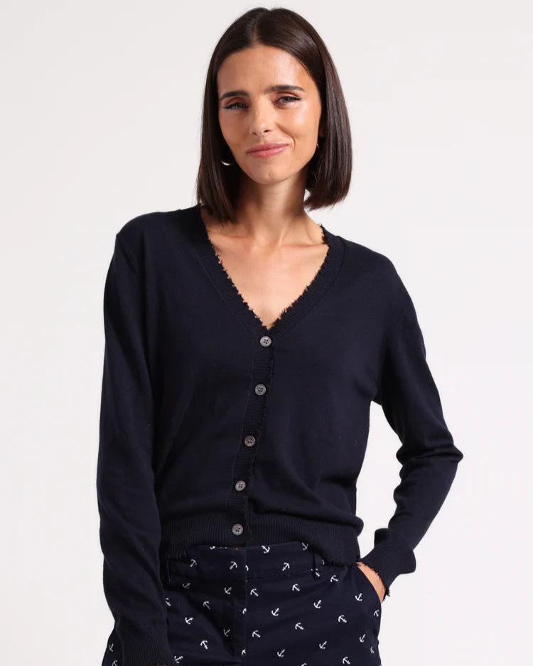 Woman wearing a navy cardigan and patterned shorts on a white background