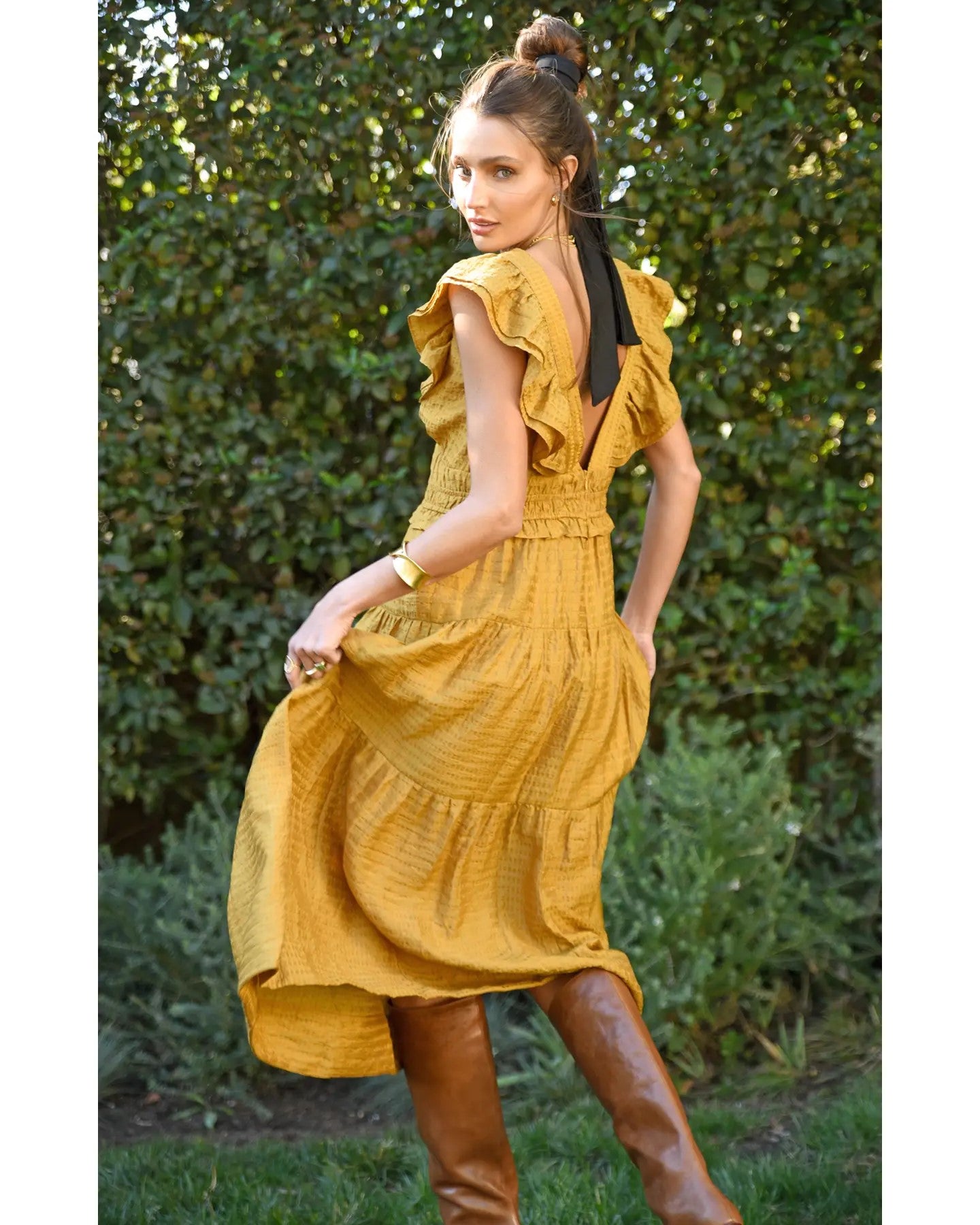 Model wearing Greylin Mustard Kalista Textured Midi Dress wearing brown boots standing outside 