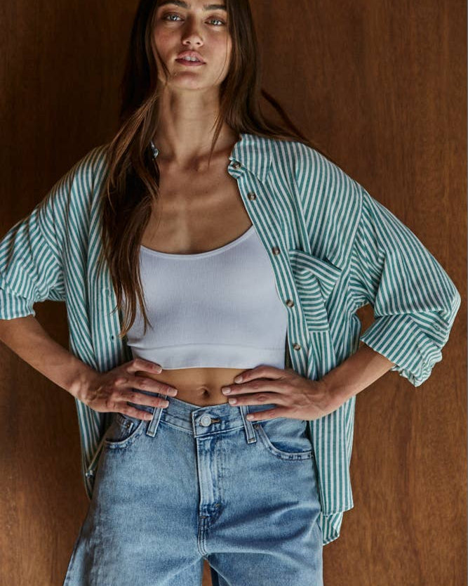 Woman wearing the By Together Woven Cotton Button Down in Green against a wooden background