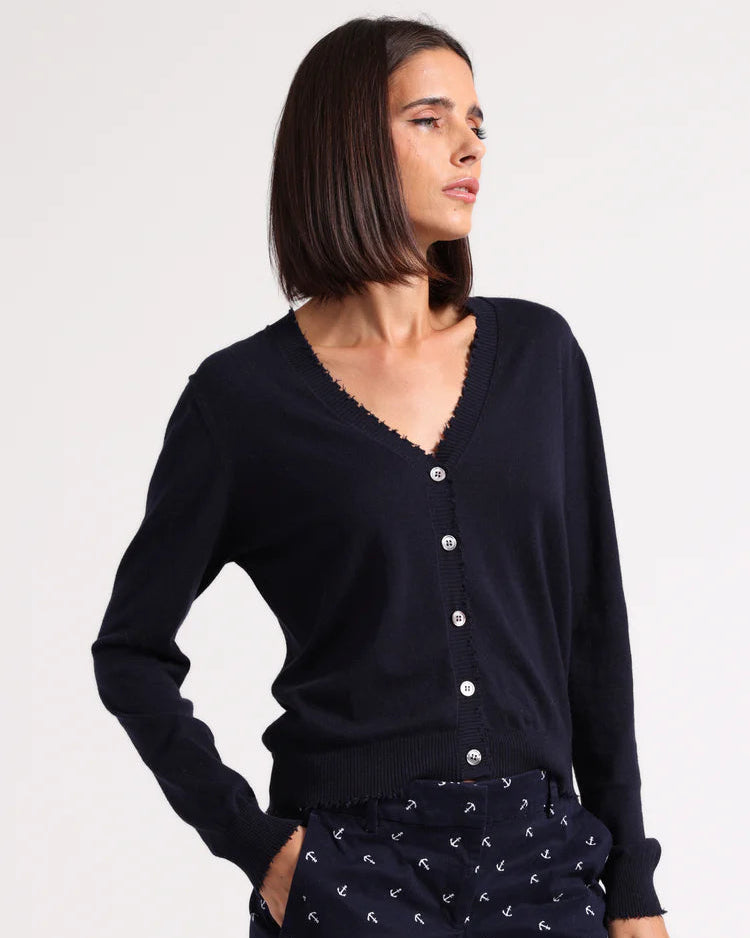 Woman wearing a black cardigan and navy shorts with white patterns on a light gray background