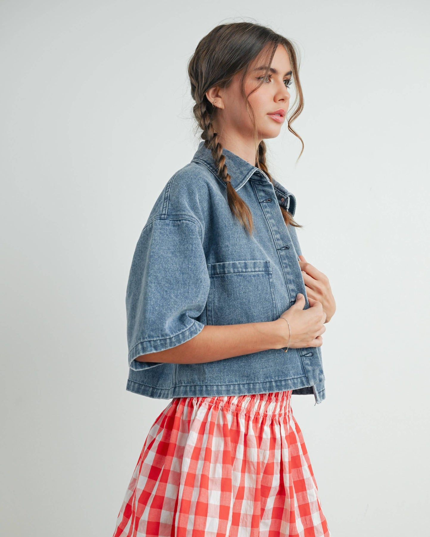 Woman wearing a denim jacket and red plaid skirt on a white background