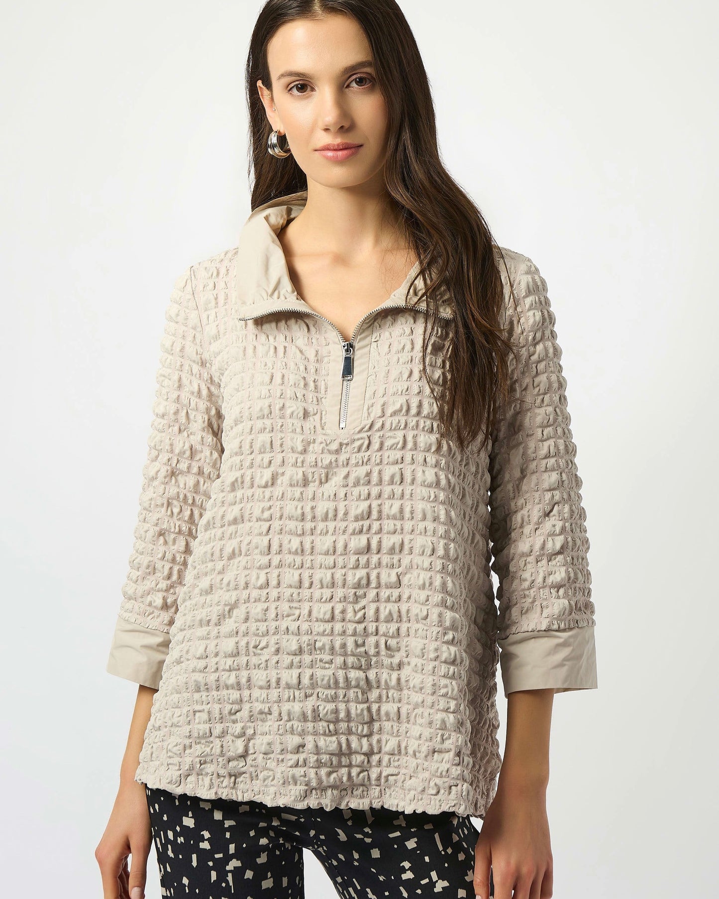Model is wearing Joseph Ribkoff Bubble Jacquard A-Line Top in color moonstone with tan and black pants on a white background