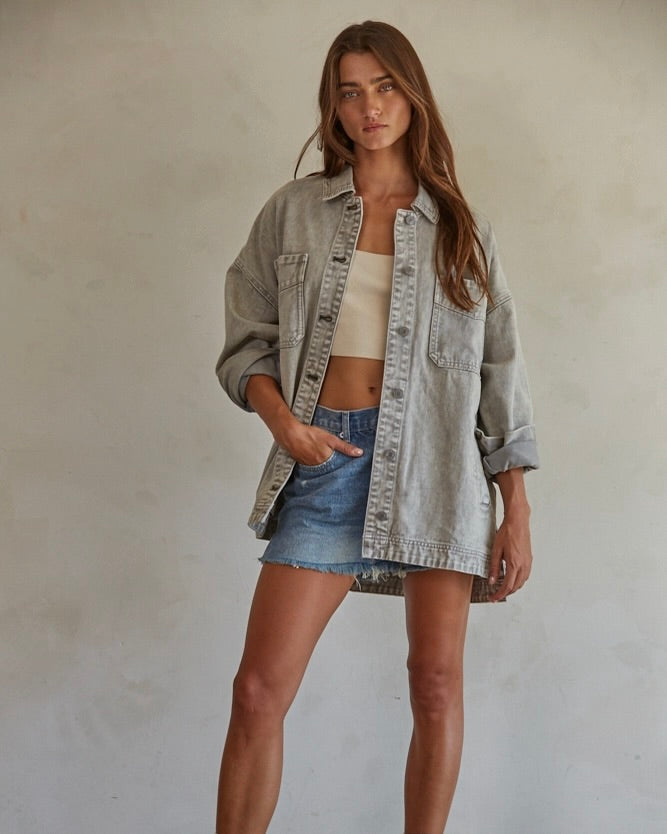 Front view of a model wearing the By Together Woven 100% Cotton Washed Denim Jacket standing in front of a beige wall