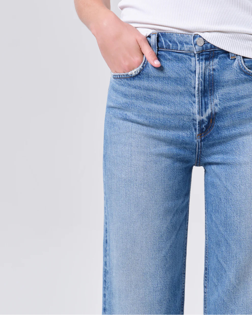 Person wearing light blue jeans with a plain background