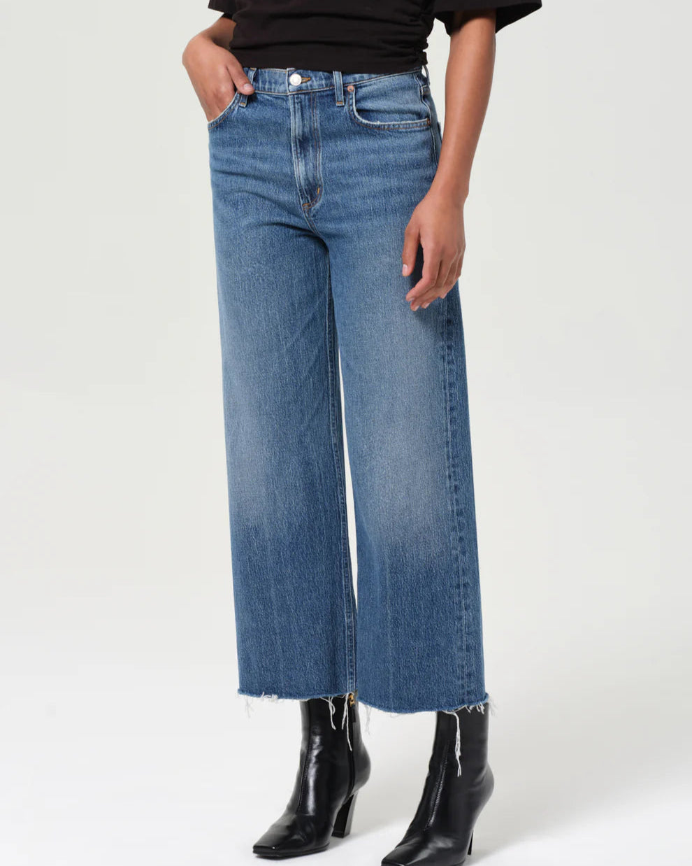 Person wearing blue wide-leg jeans and black boots on a white background