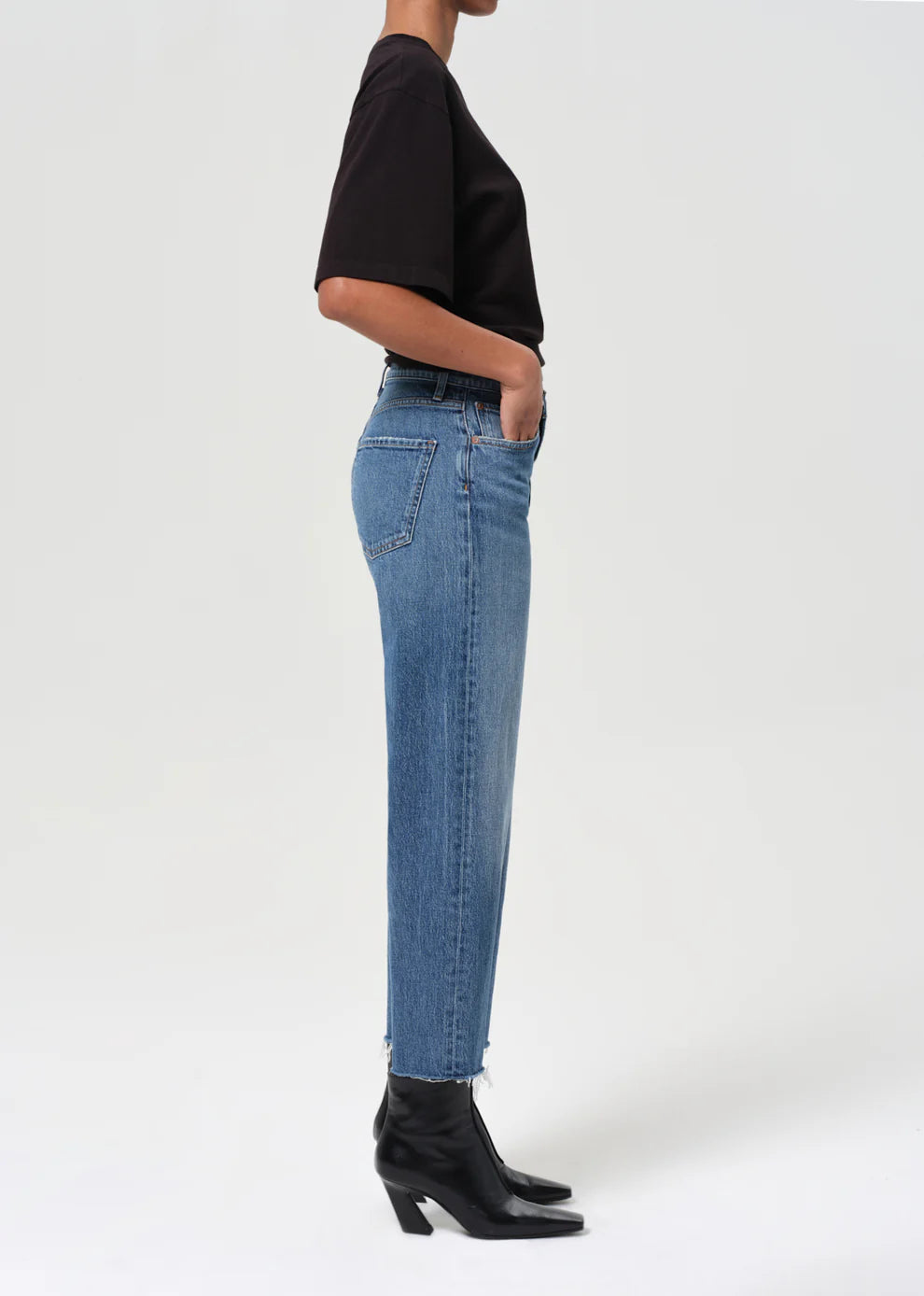 Person wearing blue jeans and black shoes on a white background