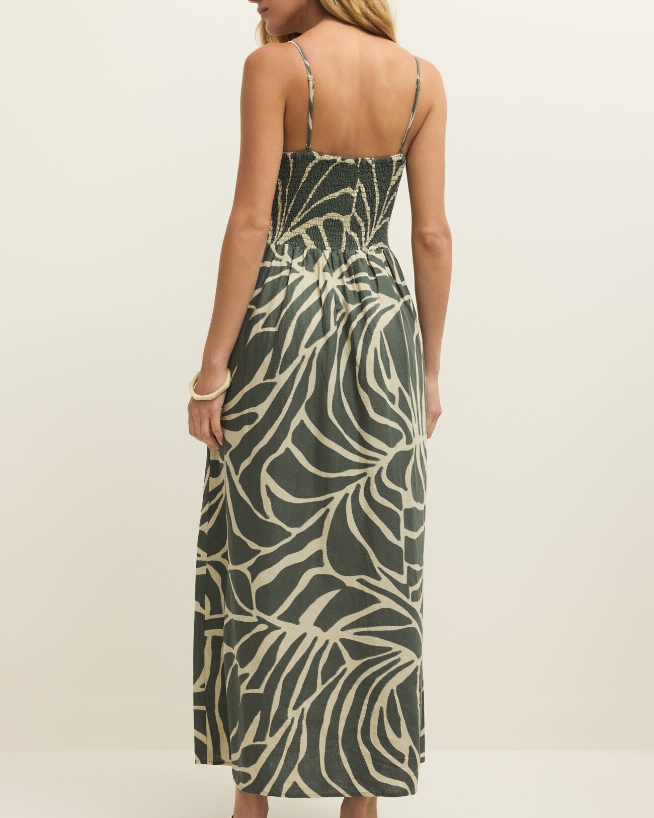 Woman wearing a long, patterned dress on a plain background