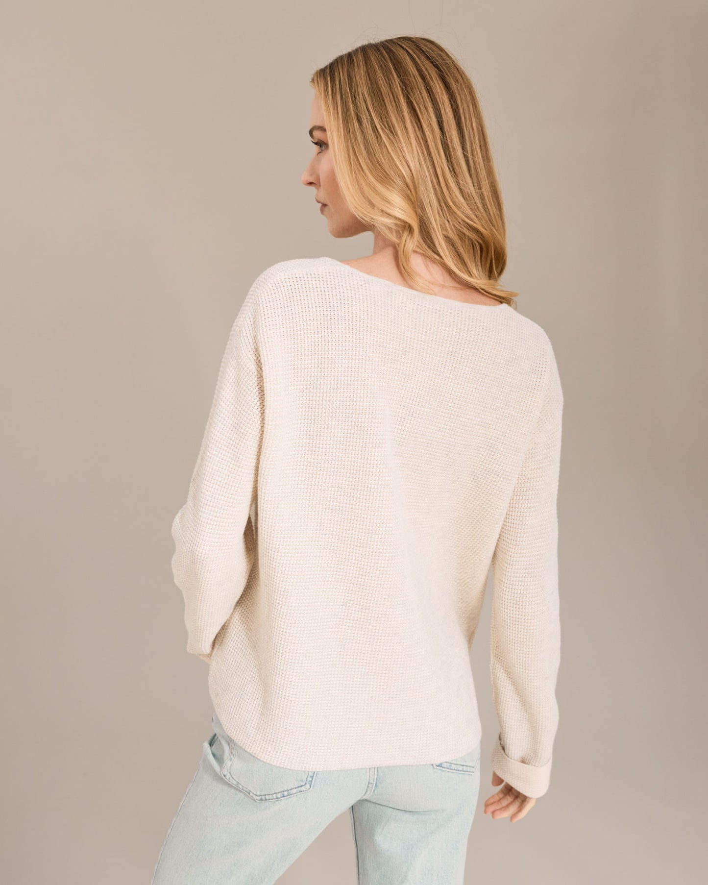 Woman wearing a cream sweater against a beige background