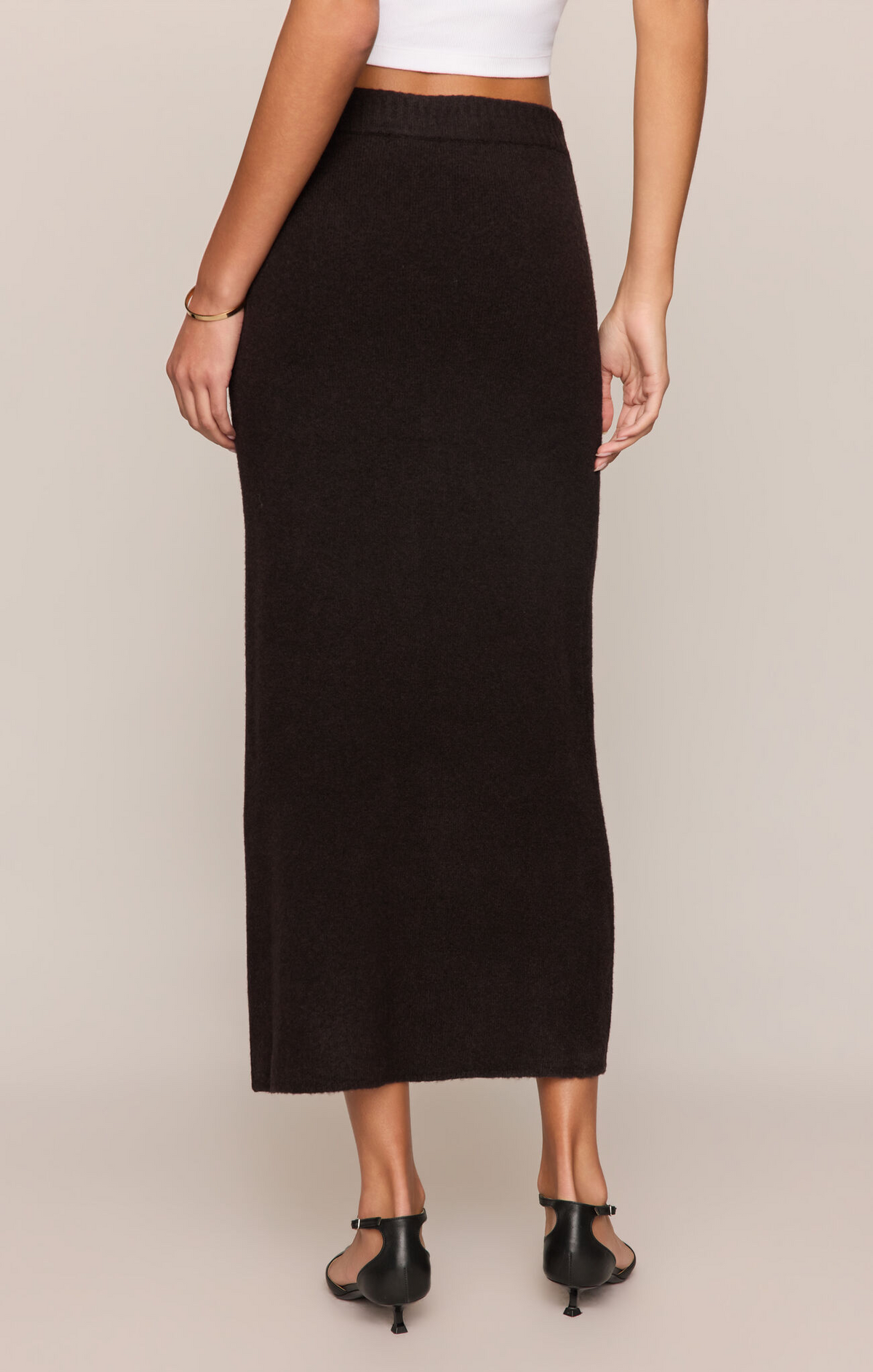 Person wearing a black skirt on a beige background