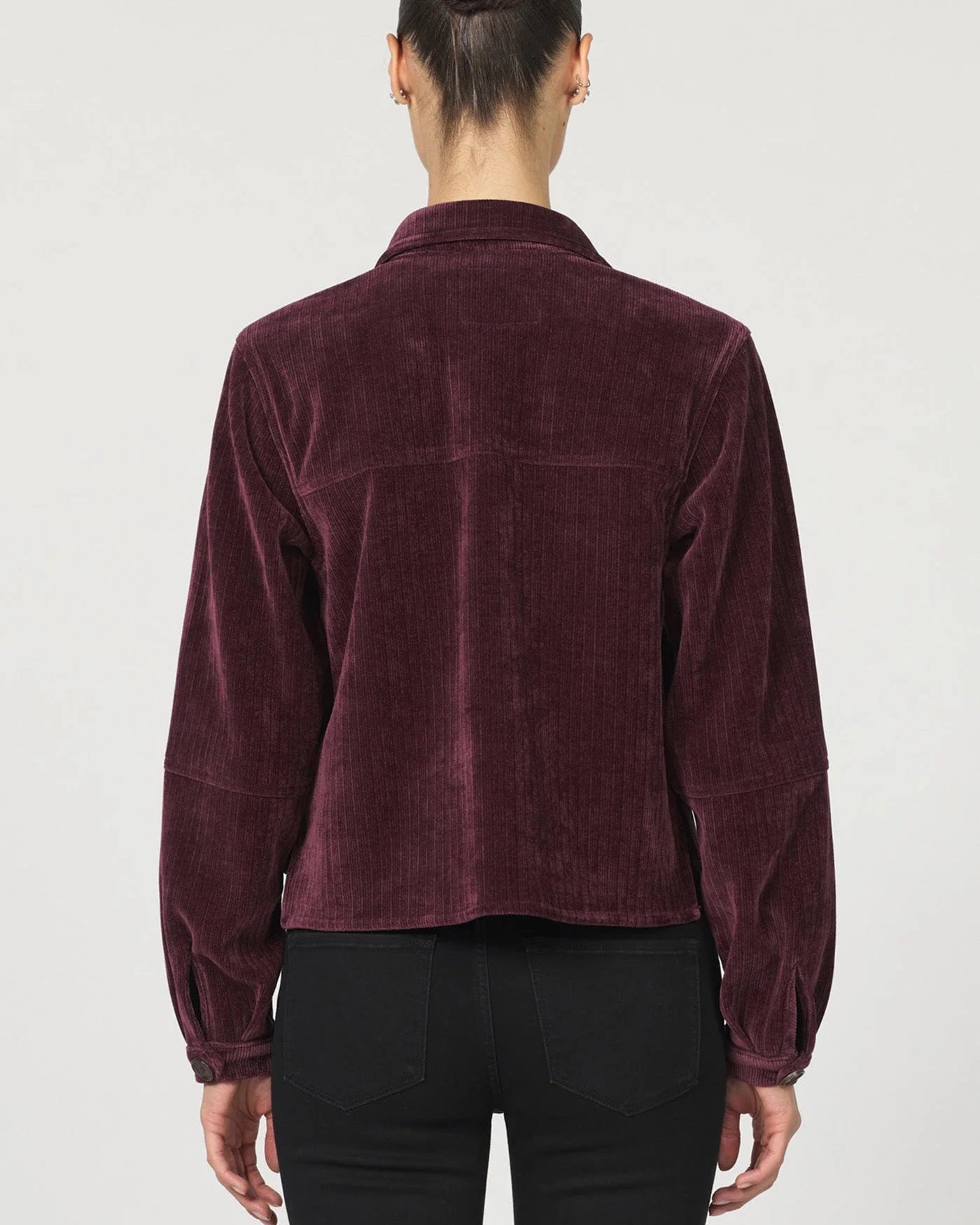 Person wearing a burgundy corduroy shirt on a white background