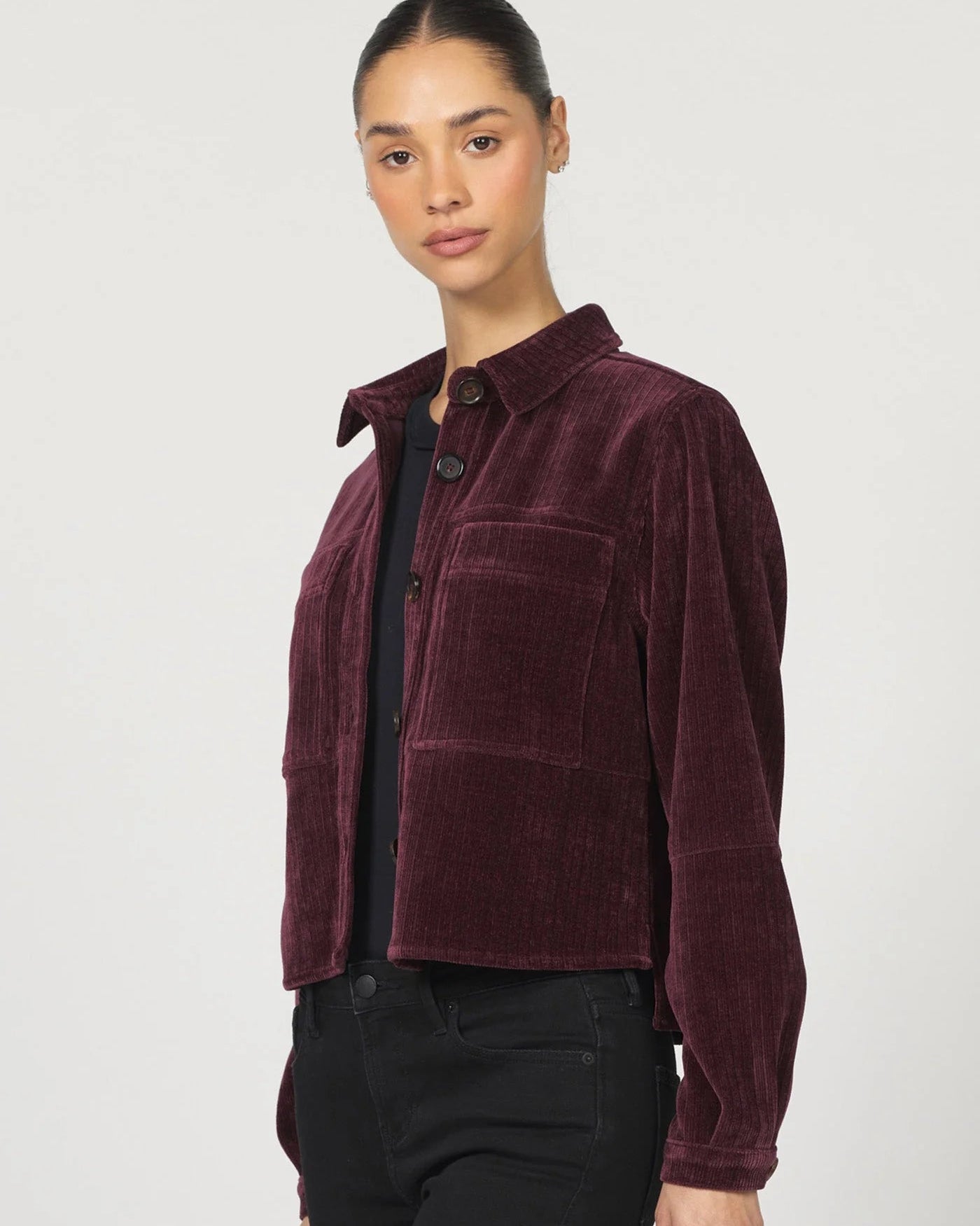 Woman wearing a burgundy corduroy shirt against a white background