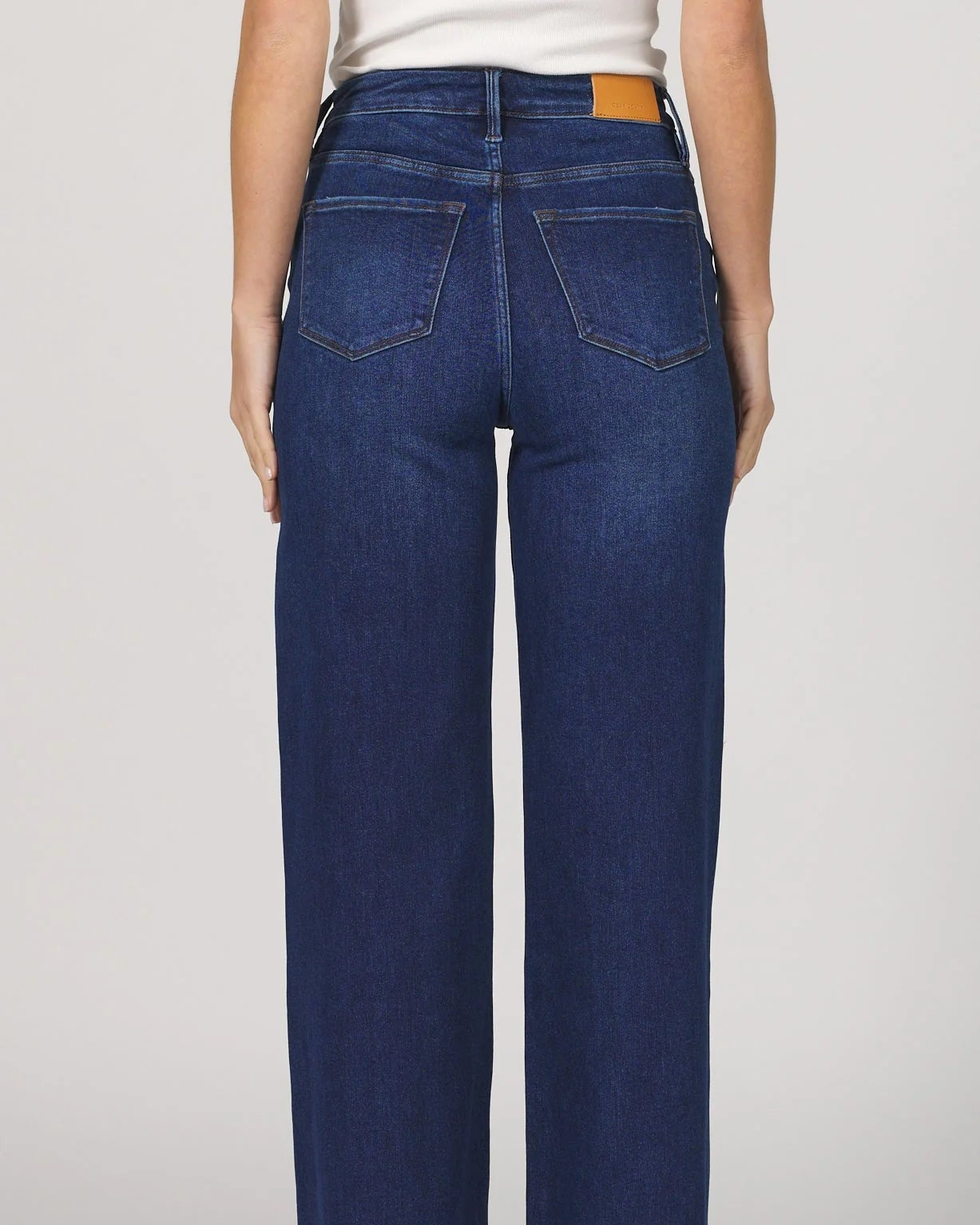 Person wearing blue jeans on a plain background