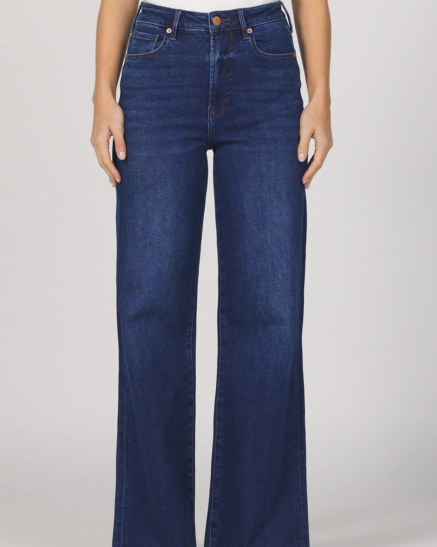 Person wearing blue jeans on a plain background