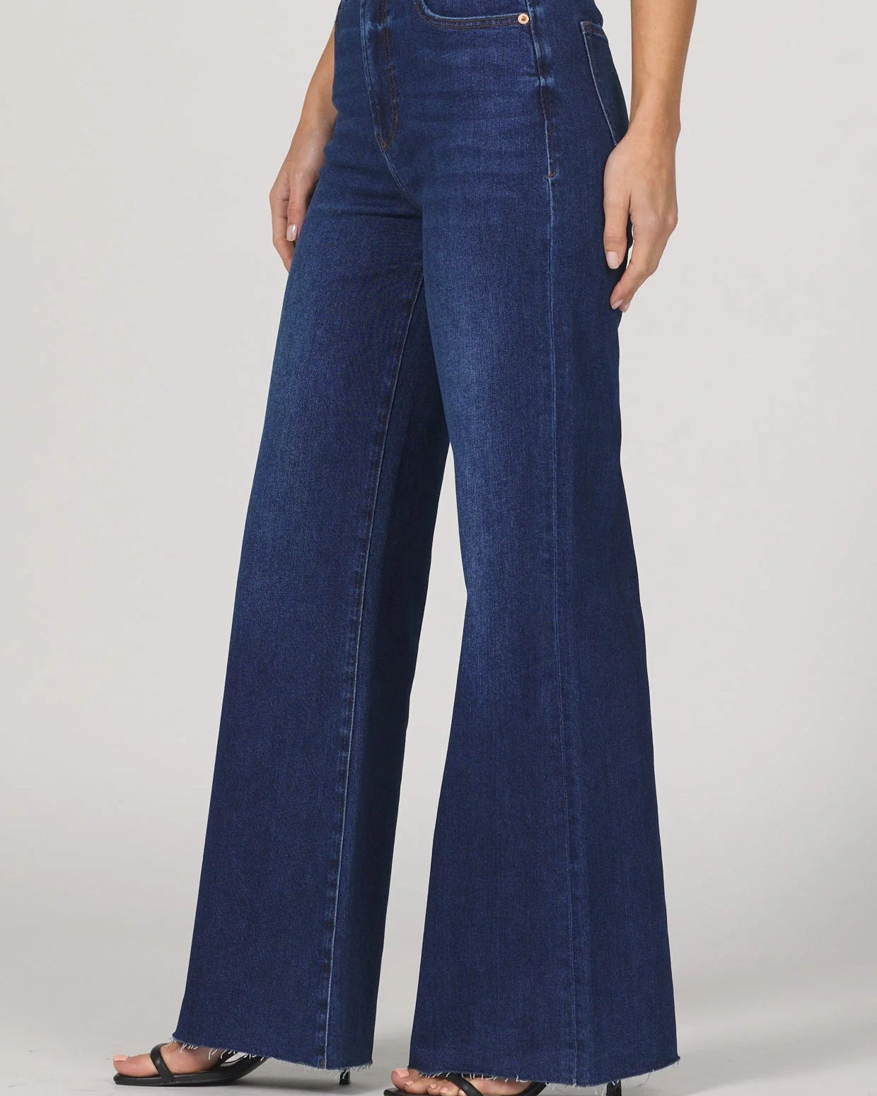 Person wearing blue flared jeans on a white background
