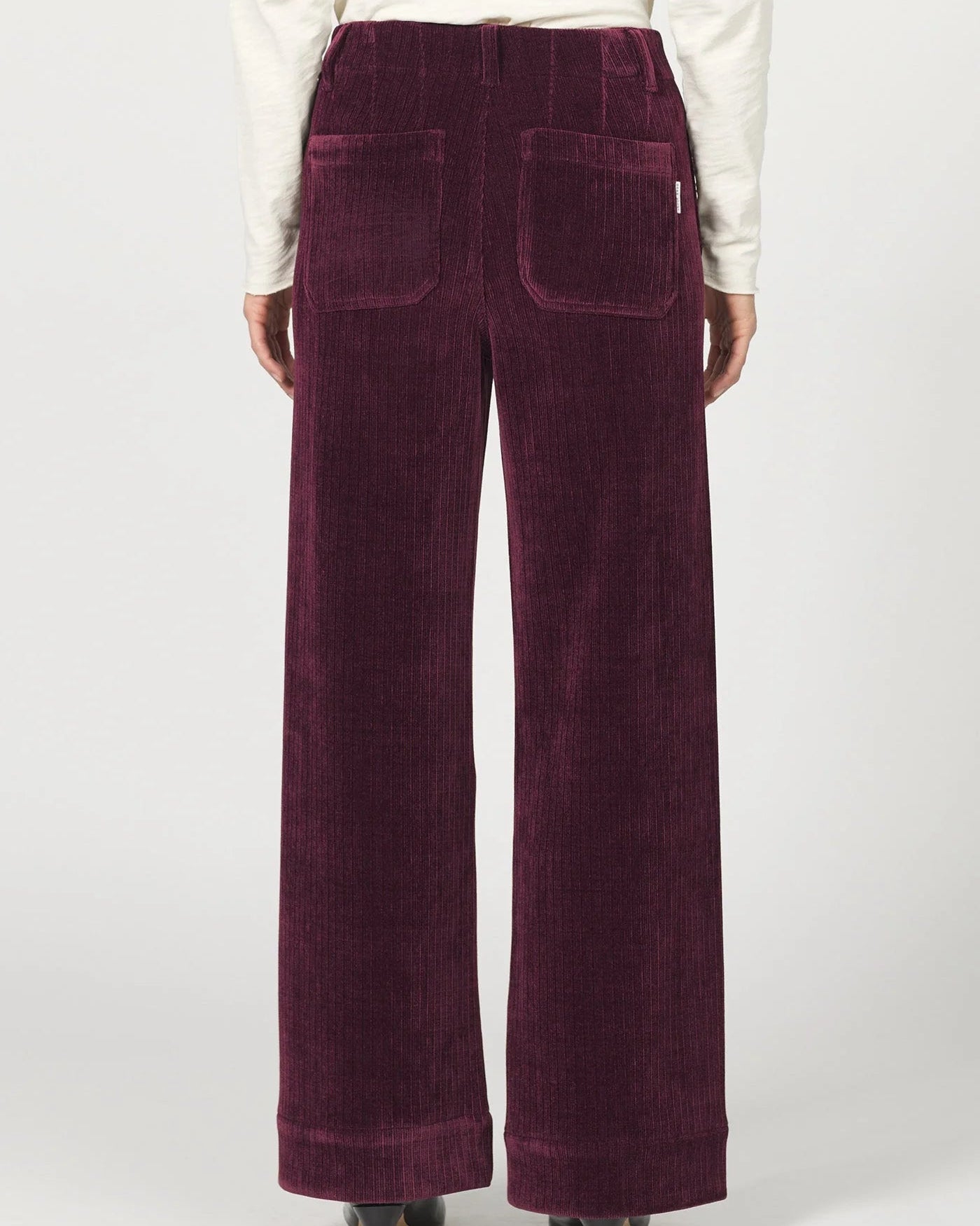 Purple corduroy pants worn by a person on a white background