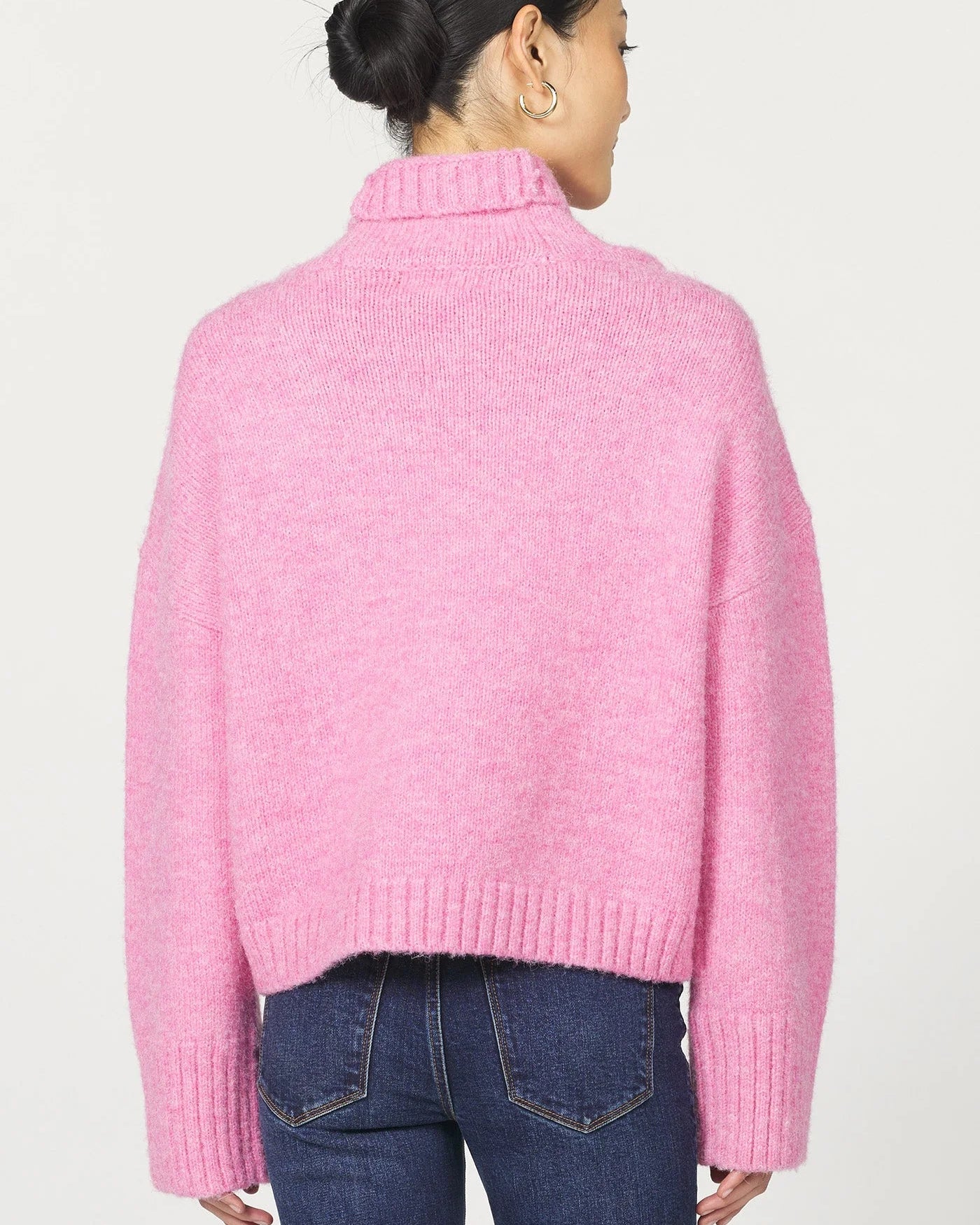 Person wearing a pink sweater and blue jeans on a white background