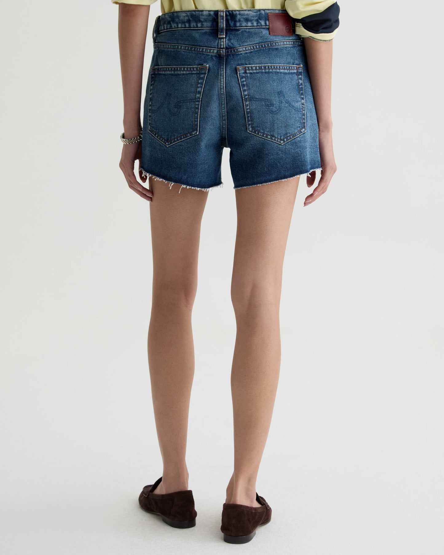 Person wearing blue denim shorts on a white background