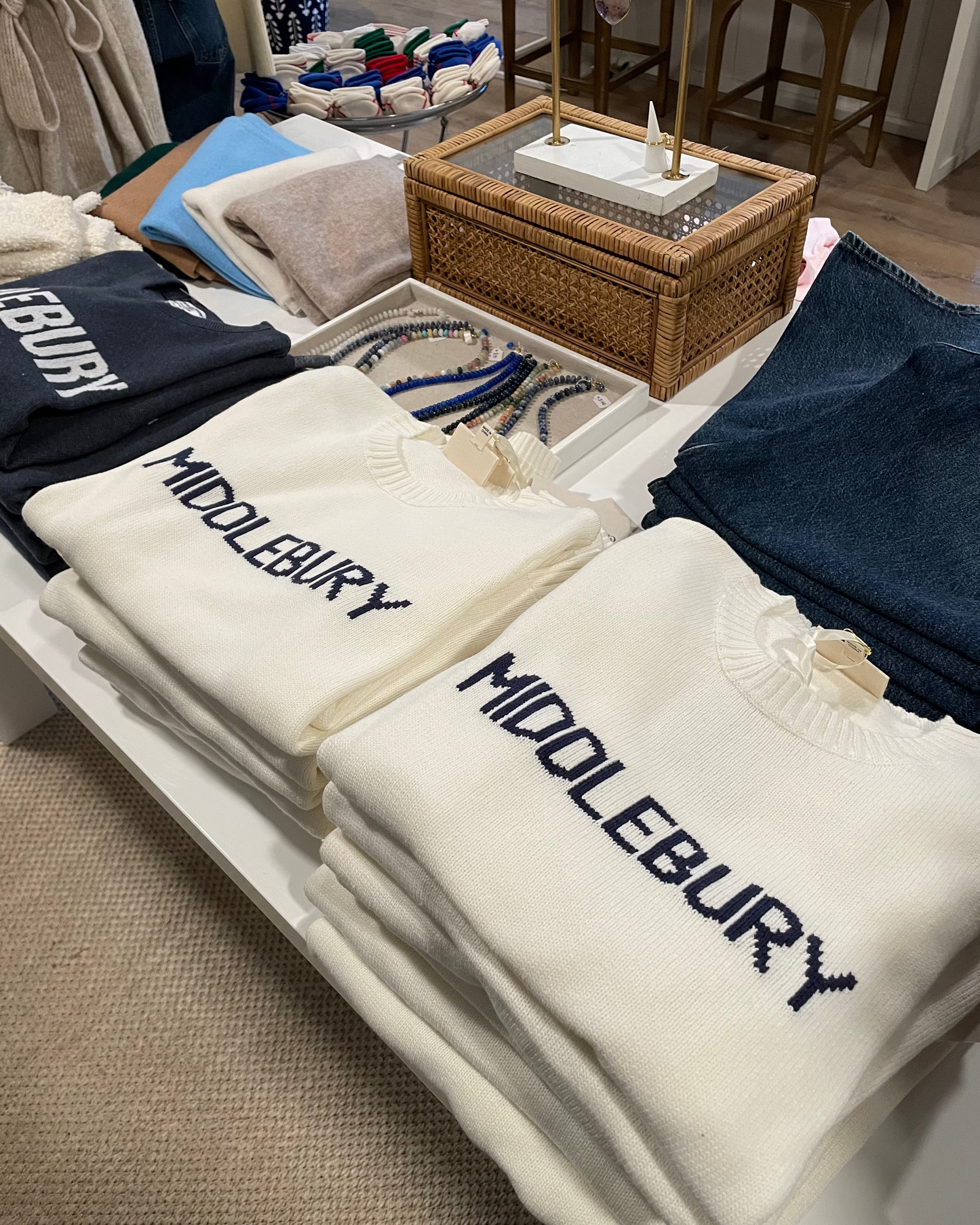 Stack of white sweatshirts with 'Middlebury' text on a display table.