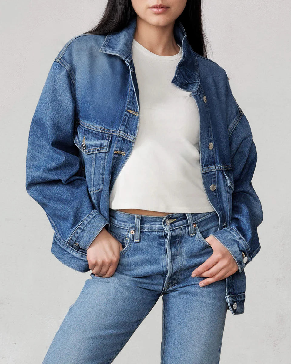 Person wearing a blue denim jacket and jeans on a plain background
