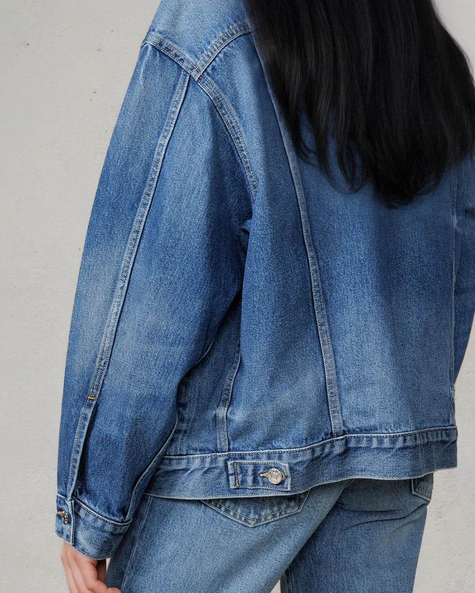 Person wearing a blue denim jacket on a plain background