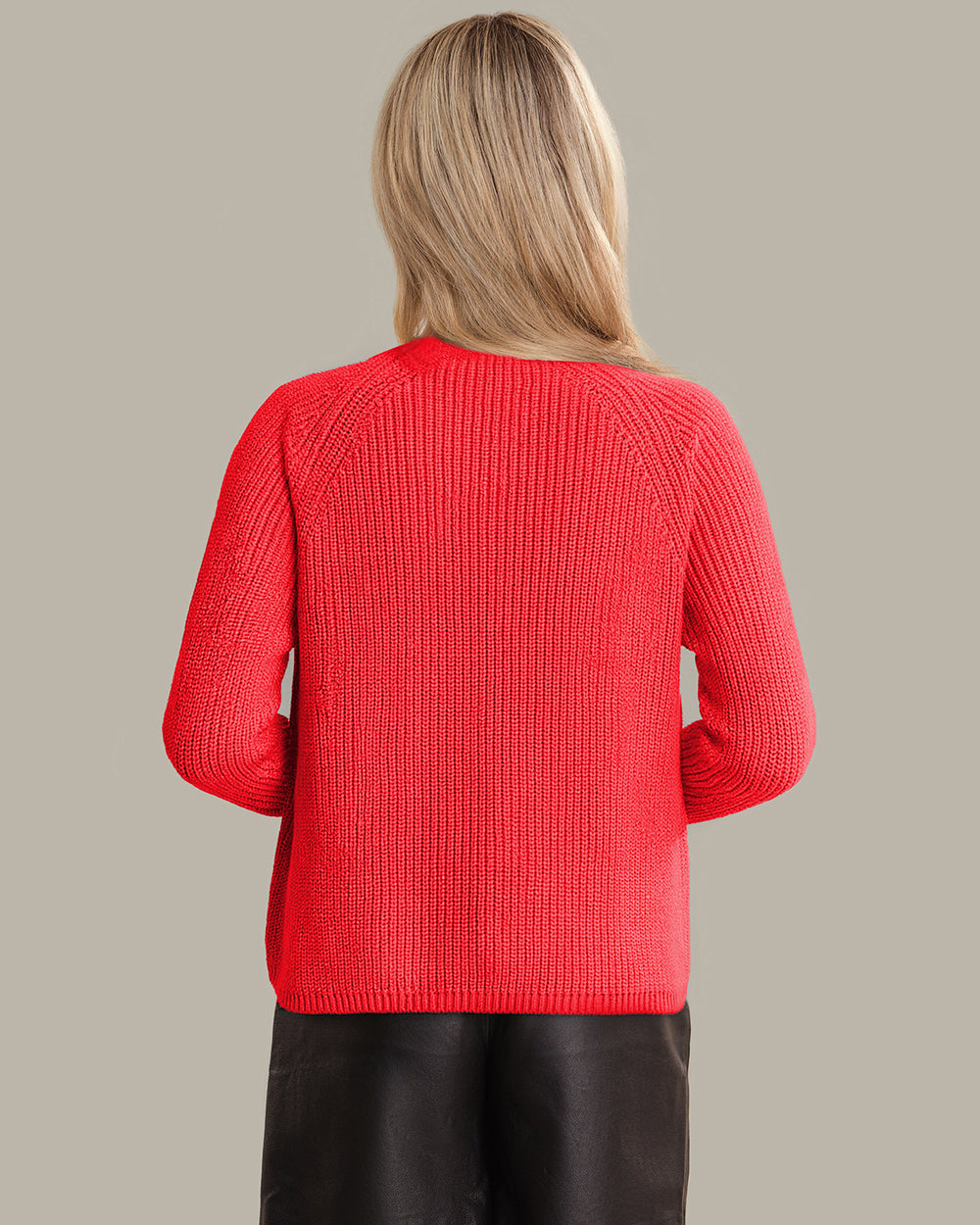 Person wearing a red sweater and black skirt on a beige background