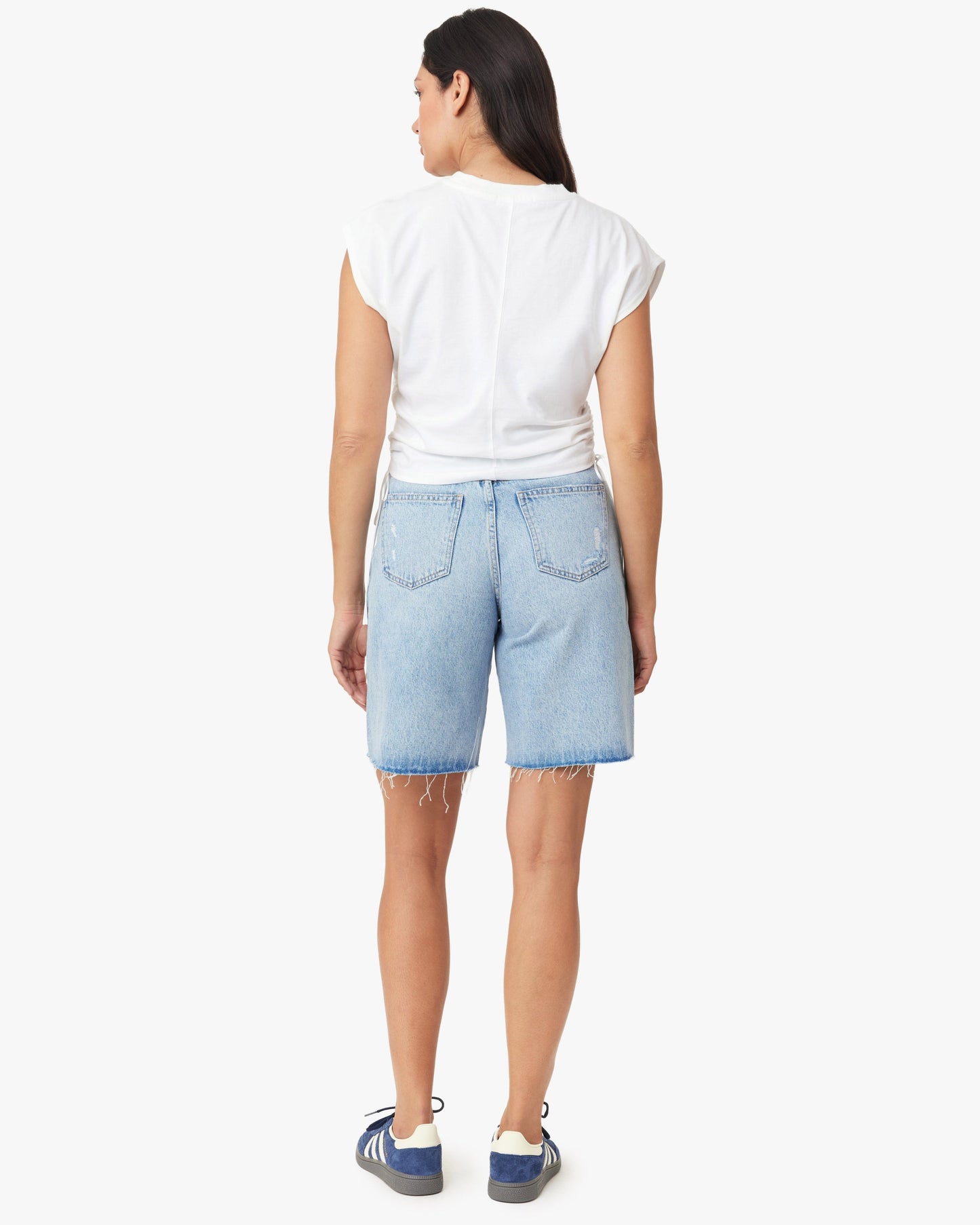 Woman wearing light blue denim shorts and a white t-shirt on a white background