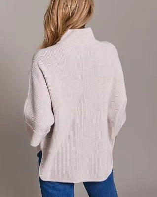 Woman wearing the Alashan Cashmere Merino Bozeman Shaker Half Zip Poncho in Buff against a gray background