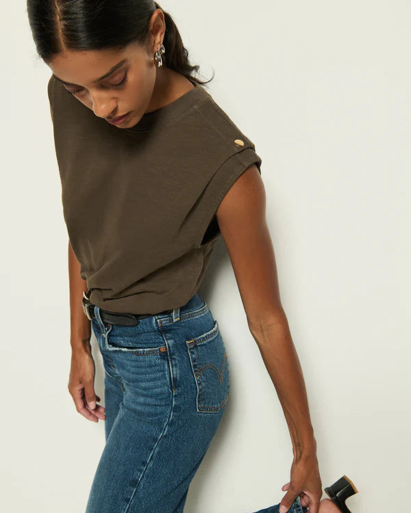 Woman wearing a brown top and blue jeans against a white background