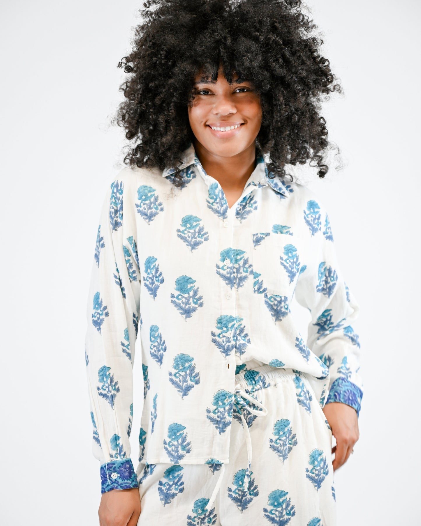 Person wearing a white robe with blue floral patterns on a plain background