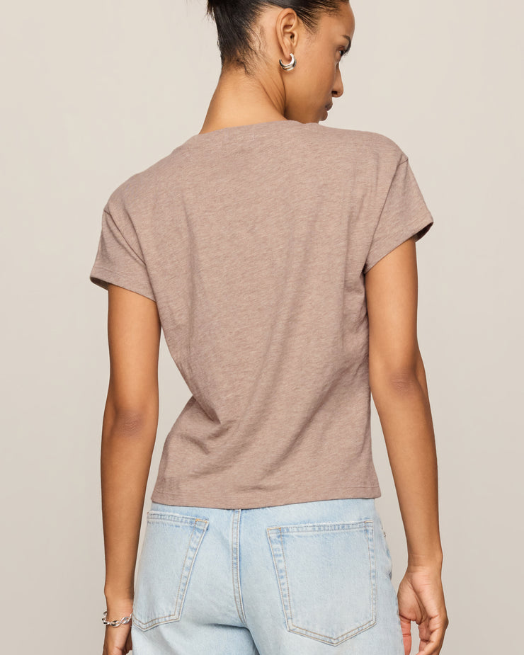 Woman wearing a brown t-shirt and light blue jeans on a beige background