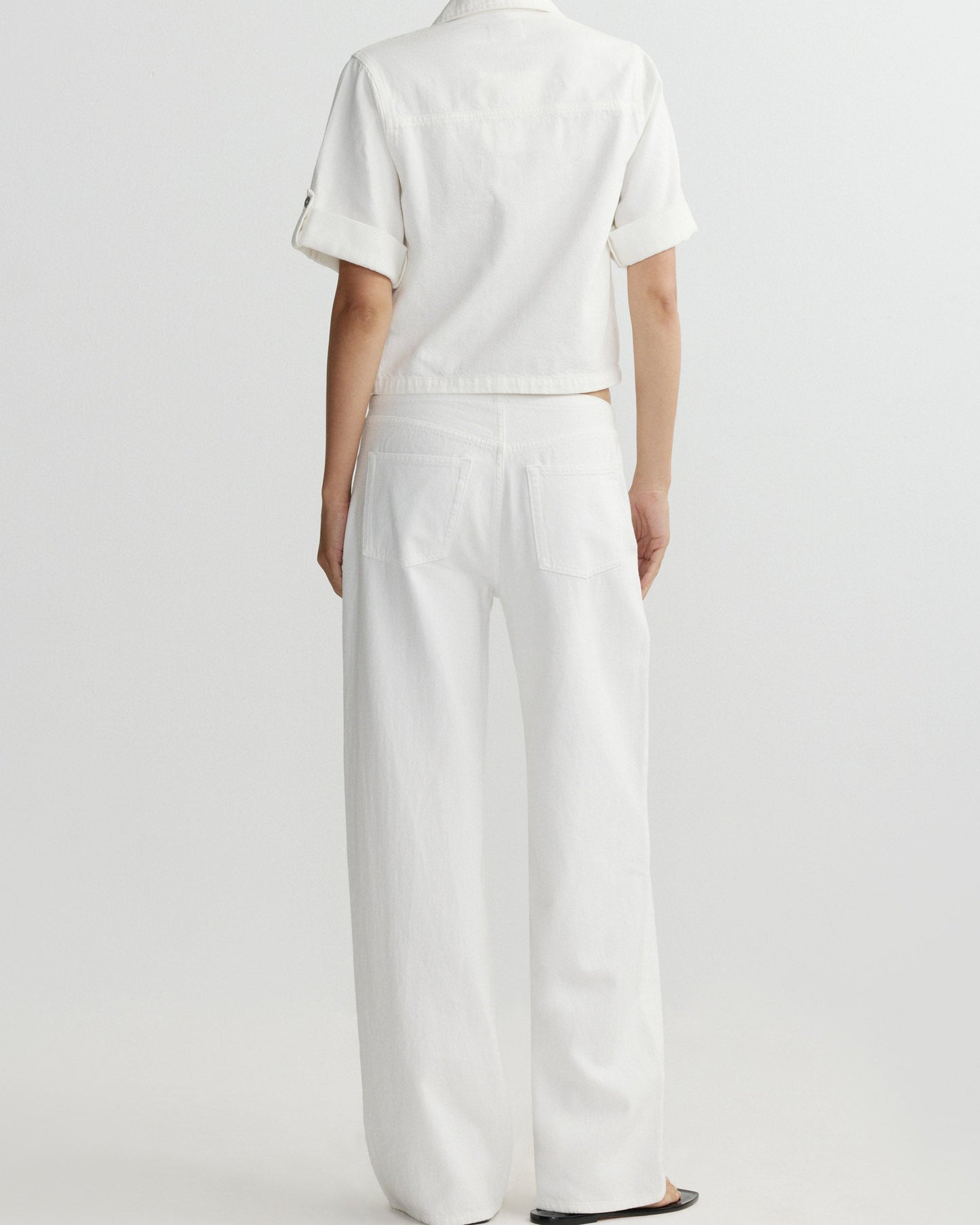 Person wearing a white outfit with a plain background