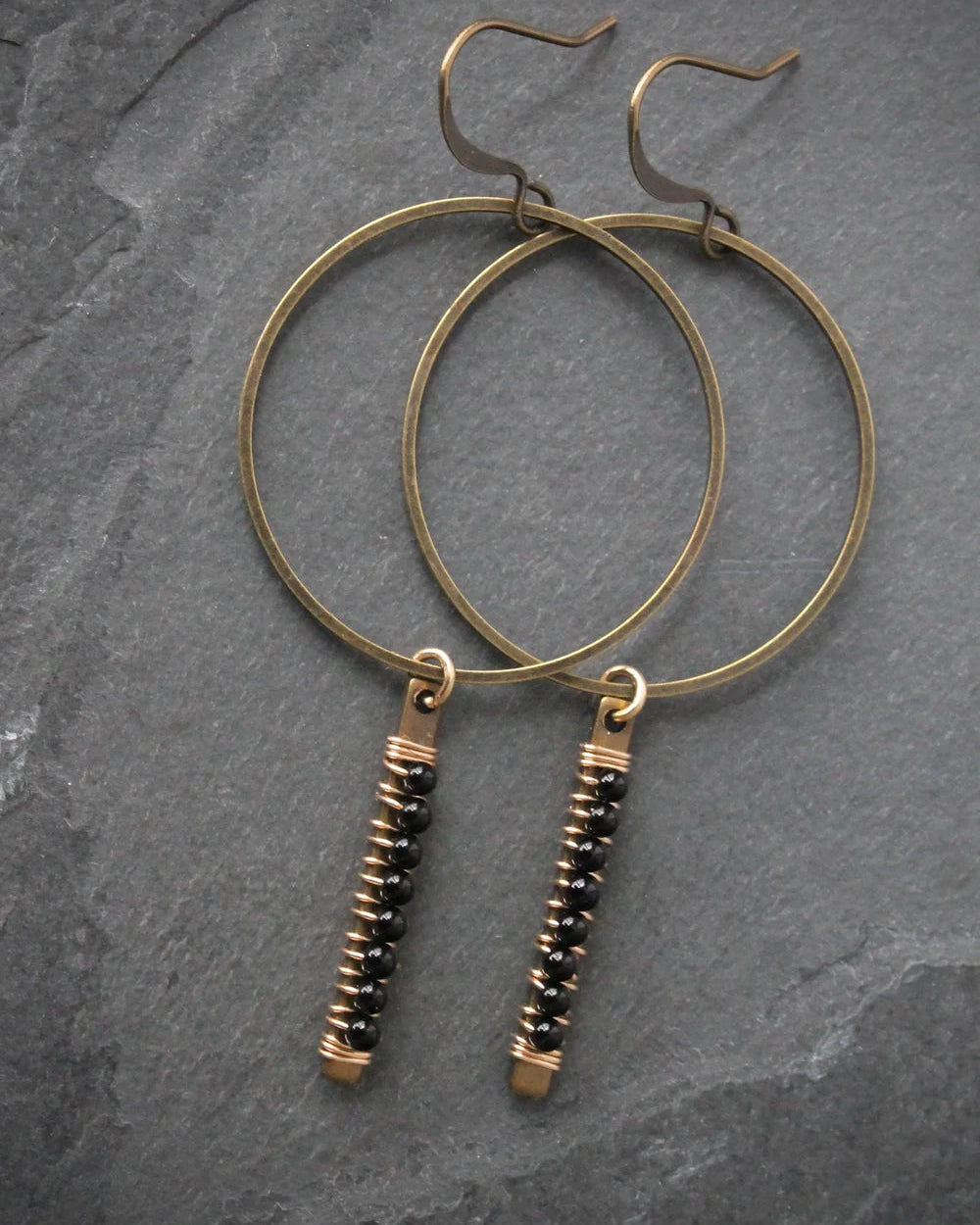 The Wild Balance Telluride Earring in the color Onyx resting on a stone