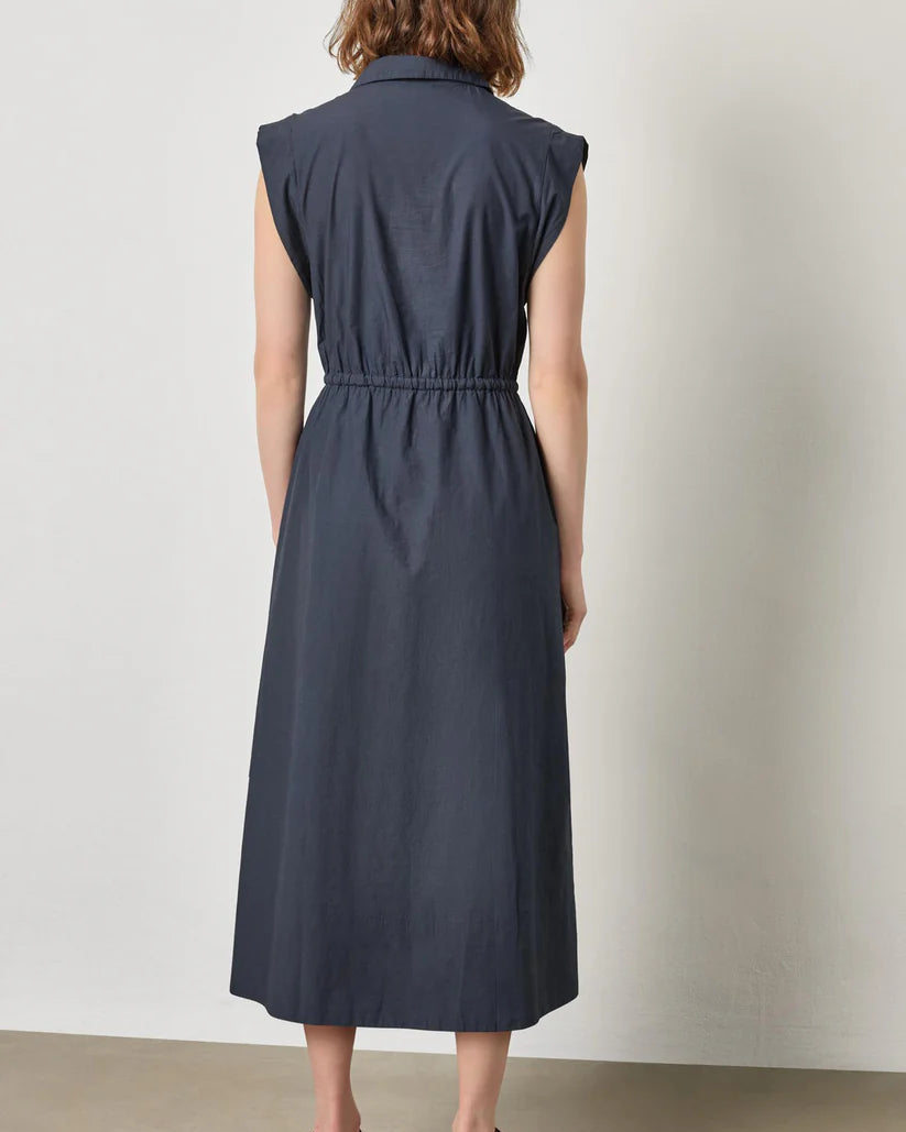 Woman wearing a sleeveless navy dress against a plain background