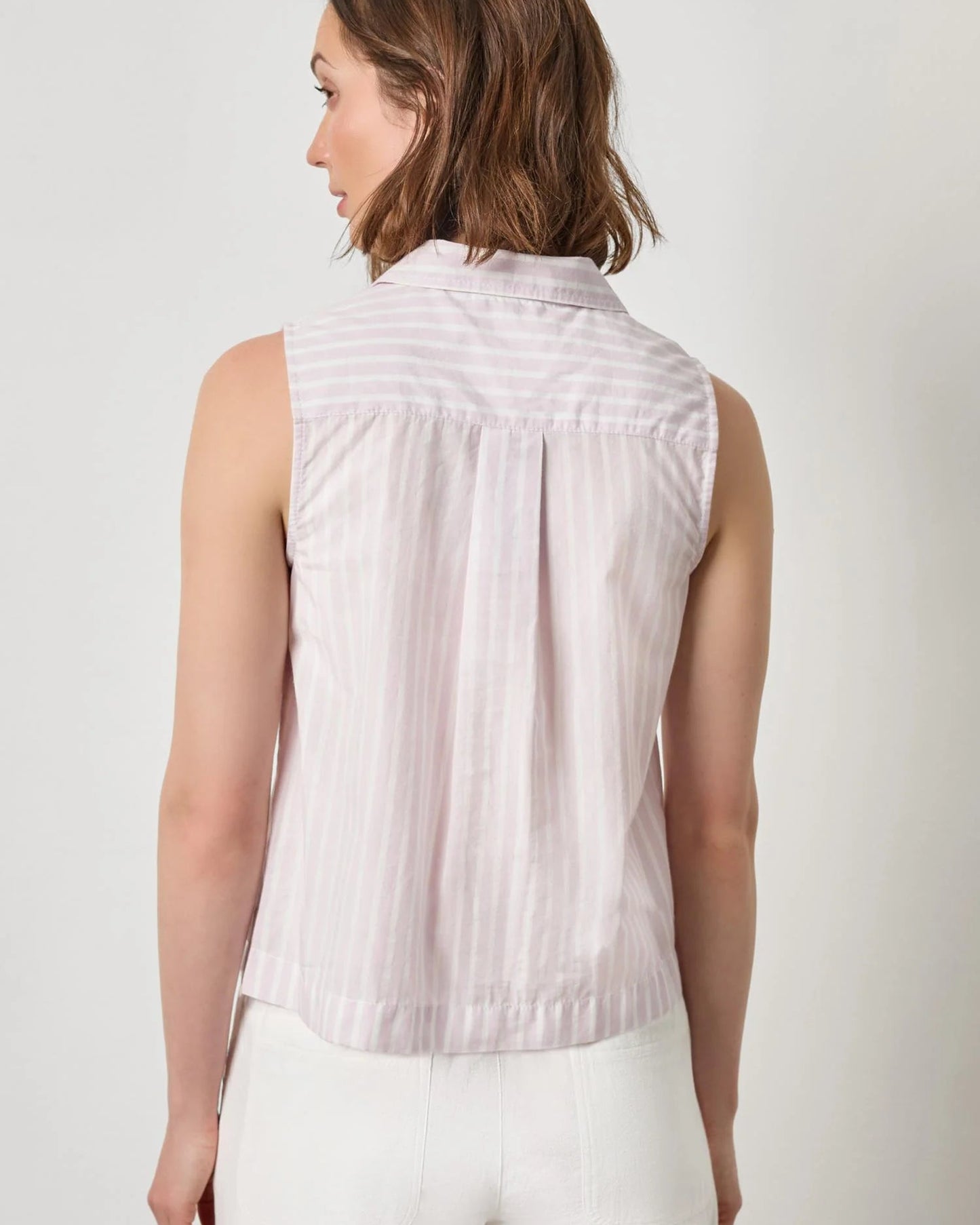 Woman wearing a sleeveless striped shirt against a plain background