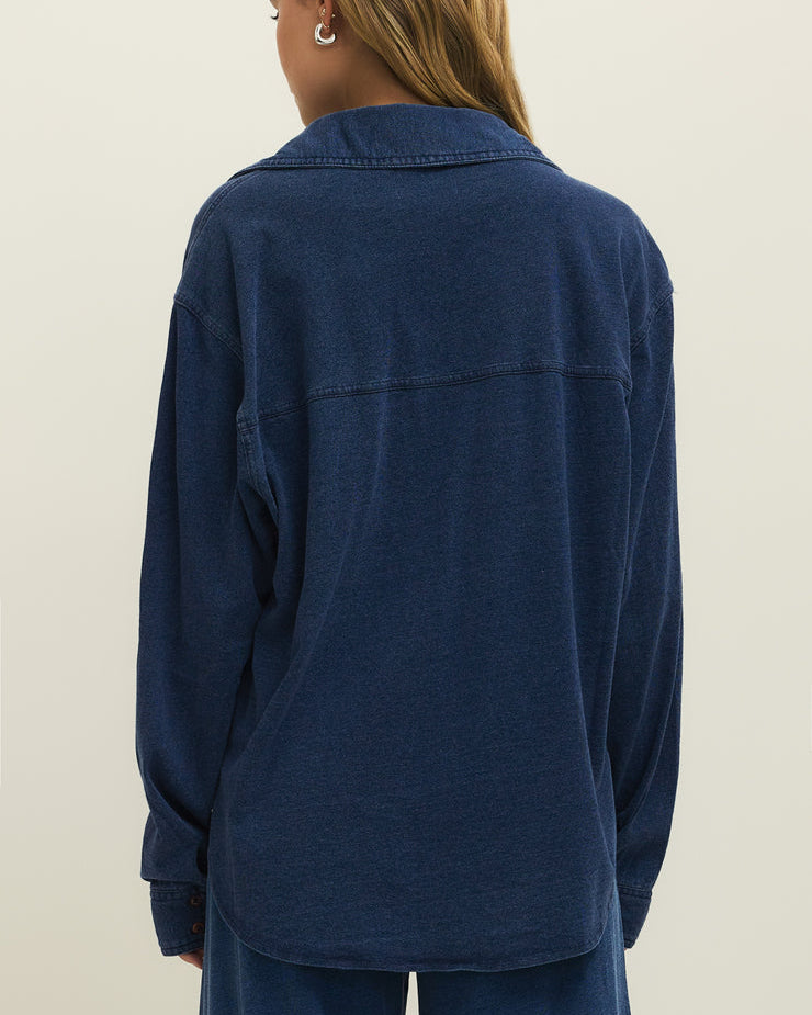 Person wearing a blue shirt and pants on a plain background