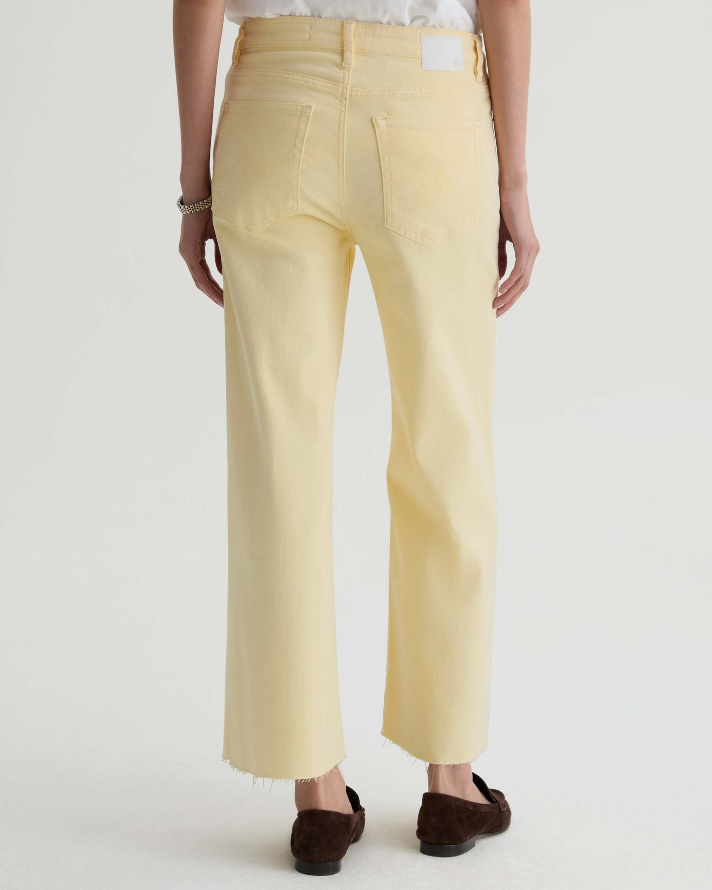Person wearing light yellow pants on a white background