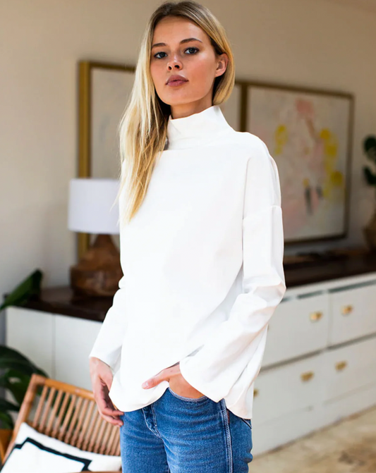 Model wearing Emerson Fry Edie Top in Ivory Ponte wearing jeans standing in her house 