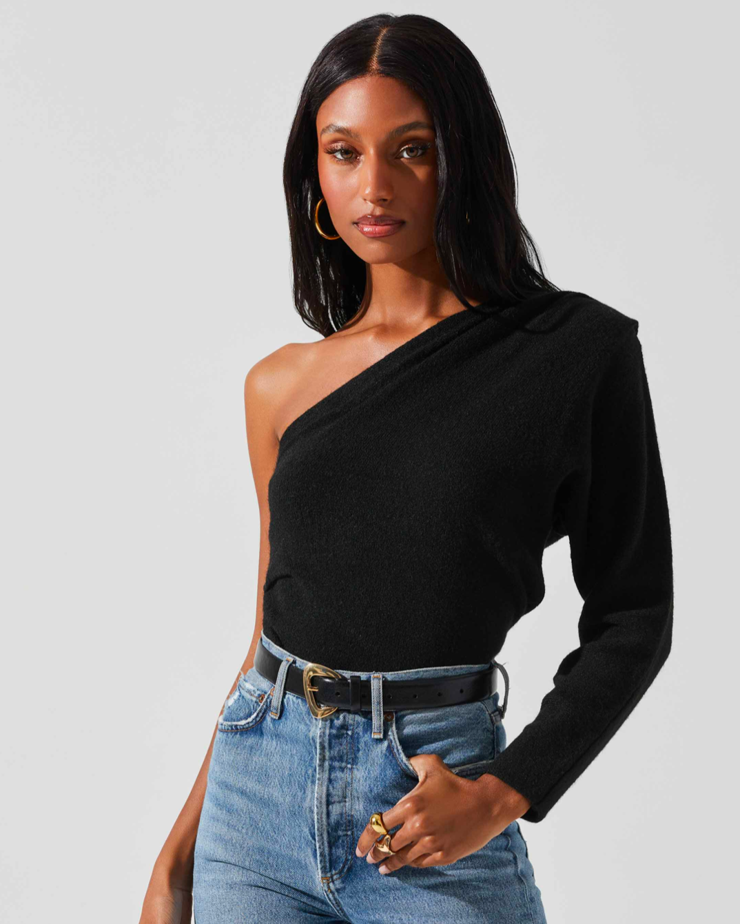 Model wearing ASTR The Label Cosima Sweater wearing jeans and a black belt on a white background