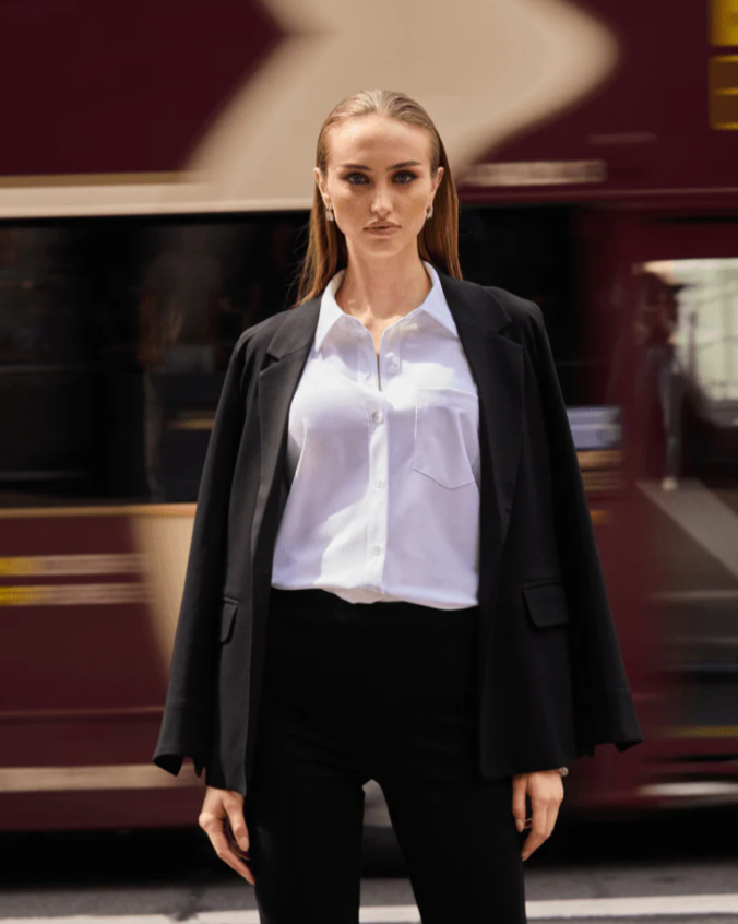 Person wearing a black blazer and white shirt in an urban setting