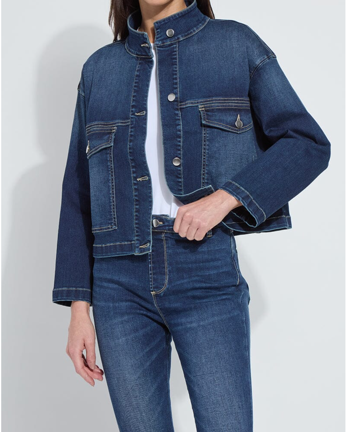 Person wearing a blue denim jacket and jeans on a light gray background